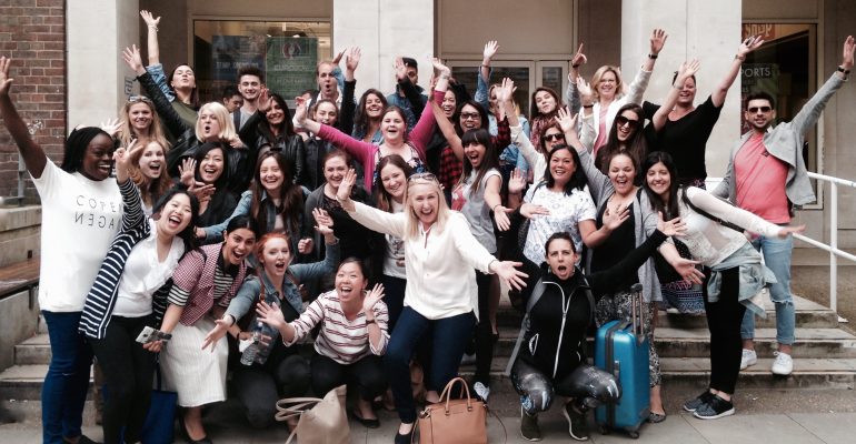 Group shot of postgraduates cheering on steps after taking their exam